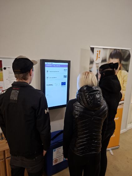 Elever framför en touchskärm på vägg