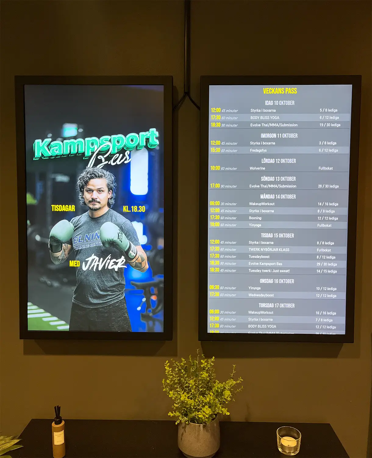 2 st digitala skyltar på vägg i gym. Ena med Zoezi-widget